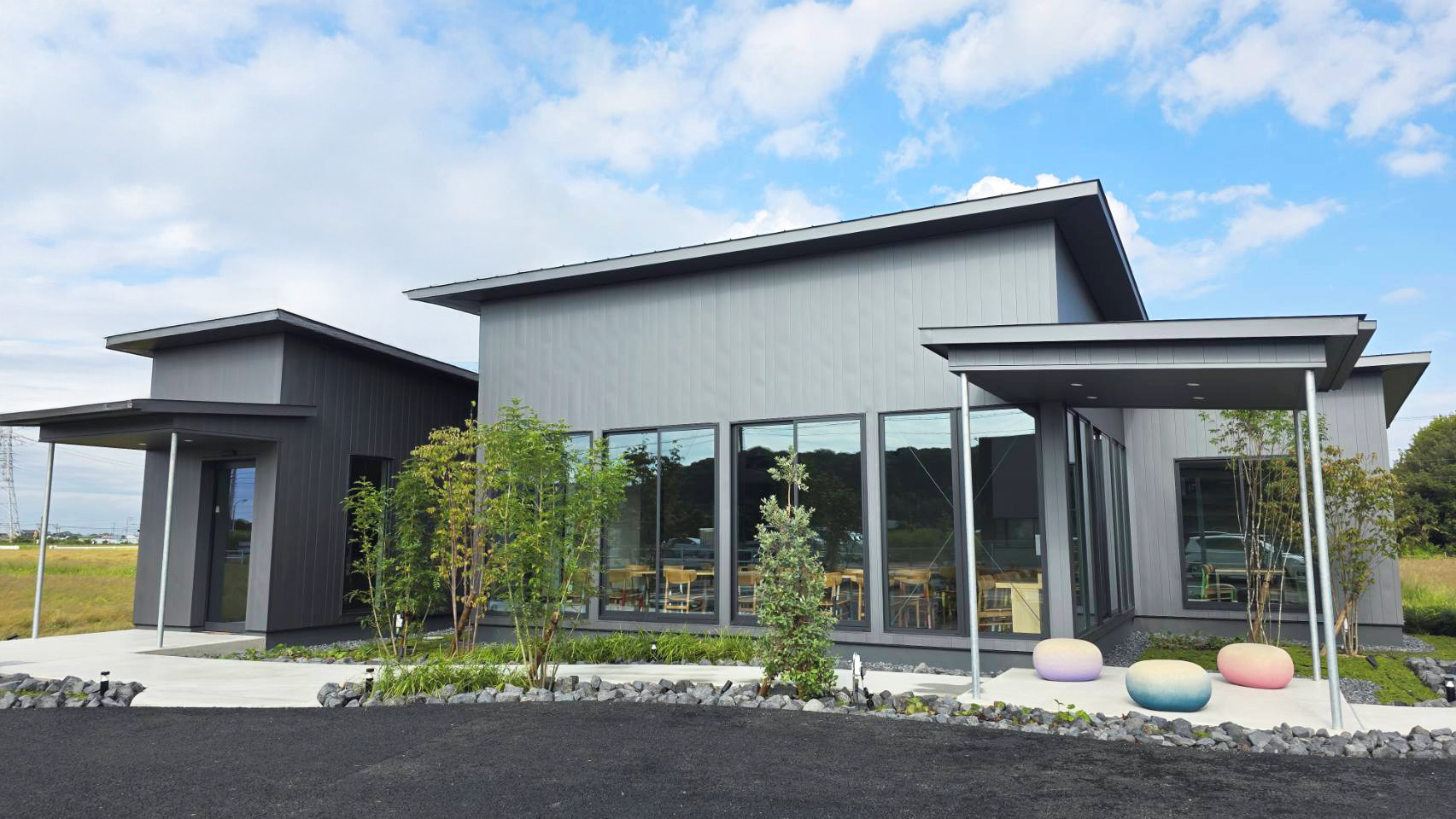 sora cafeの外観。片流れ屋根の平屋と大きな窓、入口まわりの植栽。